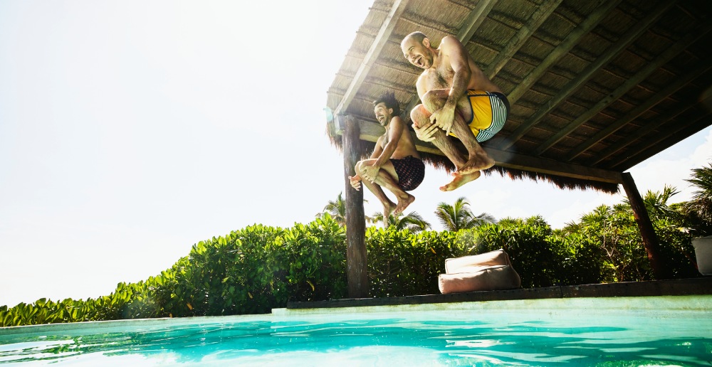 two males jumping in the pool